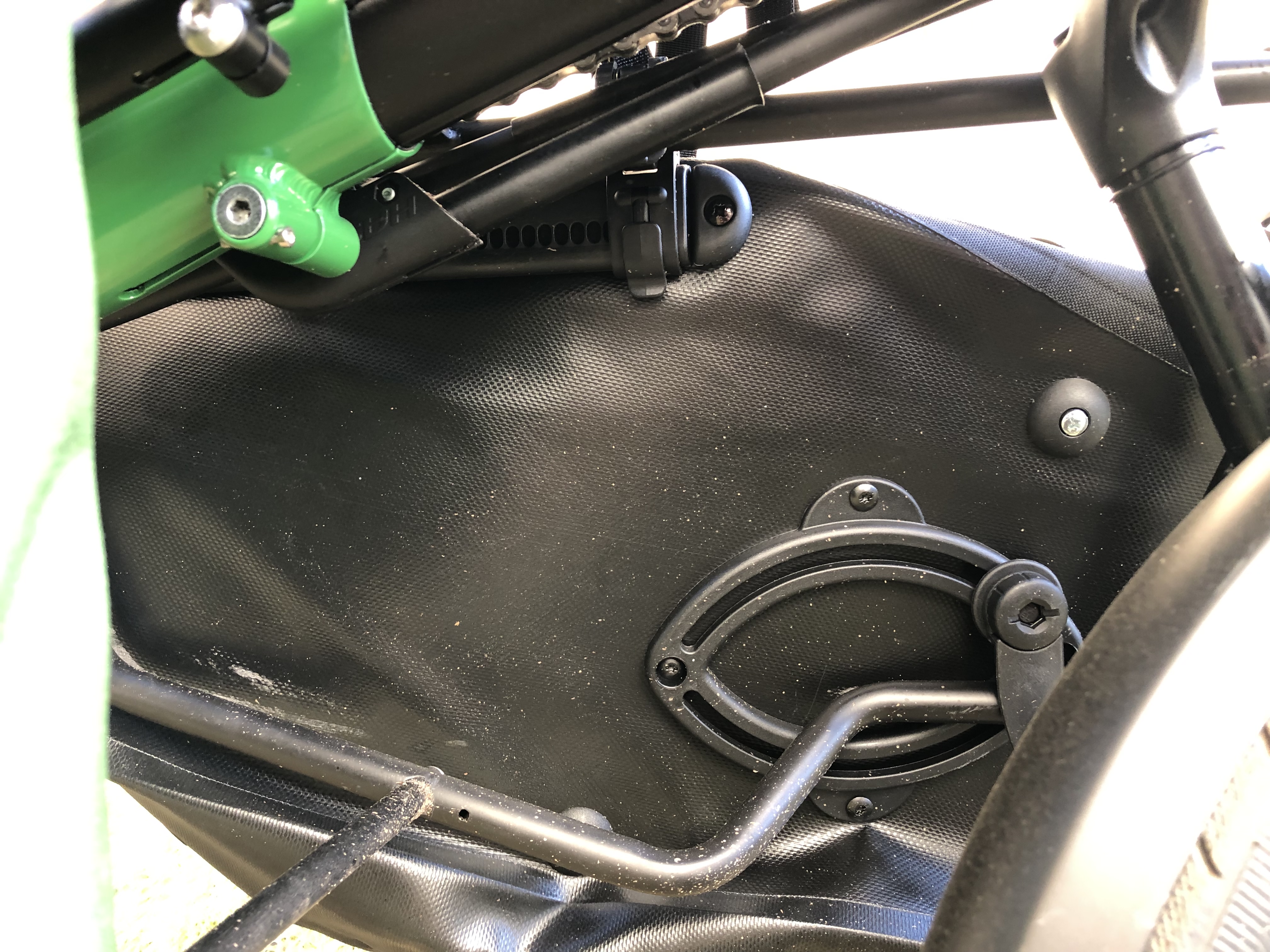 Der Versuch, die Anbrindung von rechts durchs Pino zu fotografieren. Vorn sitzt die Tasche halt mehr auf dem unteren Haken. Oben sind vorn keine Haken. Ich habe noch einen Riemen hingemacht, der aber auch nach vorn über den Lowrider rutschen kann, bis ich da als Stopper mal endlich eine Schraube in das Loch im Lowrider drehe. Da ist bei mir keine drin. Es funktioniert, aber mit zwei besser platzierten Hakenschienen an der Tasche wär das bestimmt schicker.